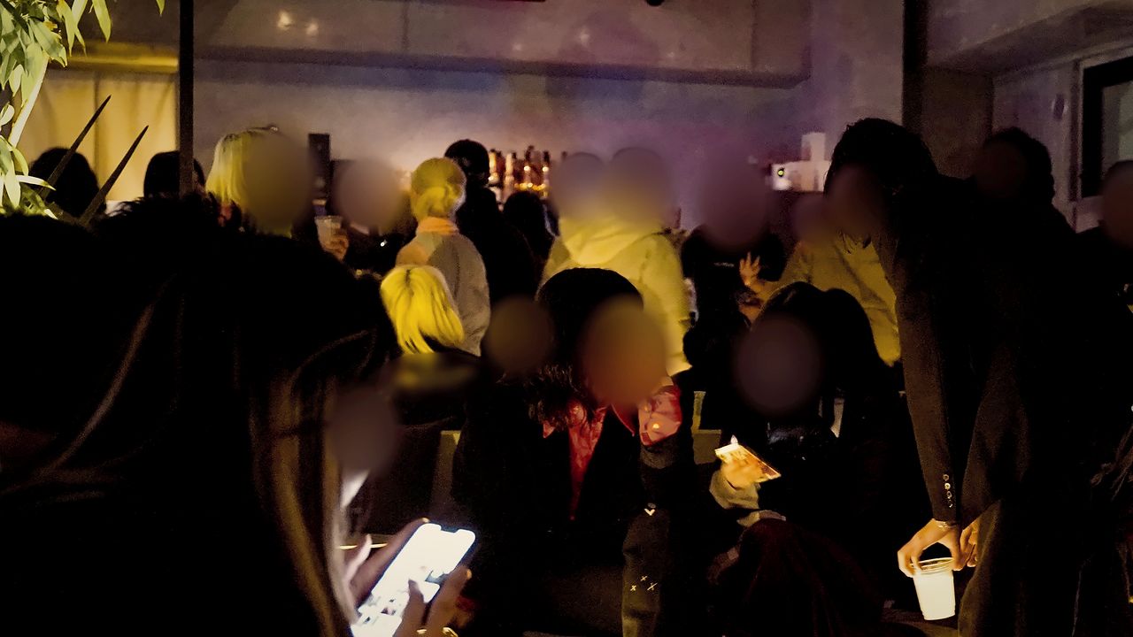 夜の会場に集まって話す人たち（イメージ写真・顔はぼかしています）